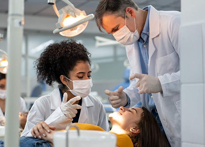 Dental hygiene student performing a supervised exam on a woman.